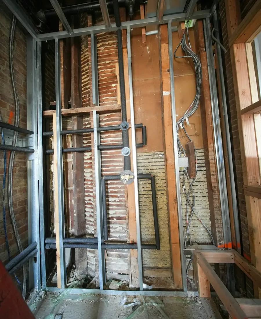 A bathroom stripped back to the joists, with the old pipework exposed