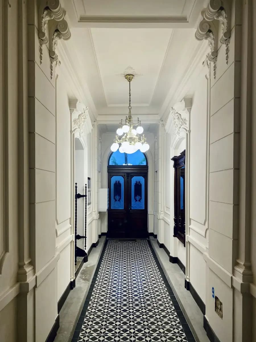 The hallway of a refurbished Victorian terrace, tiled floor and a blue front door at the end