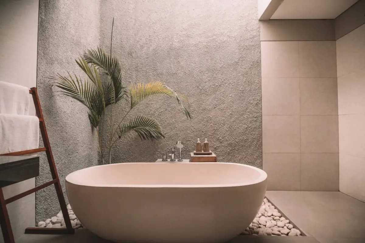 A finished bathroom with a freestanding bath against a stone wall